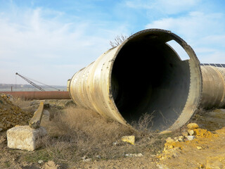 Old rye pipes of large diameter lie on the ground. Pipeline. Large iron drainage pipes connect two...