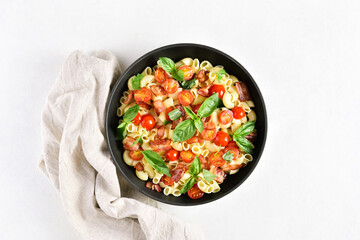 Tomato and bacon pasta with parmesan cheese and basil leaves
