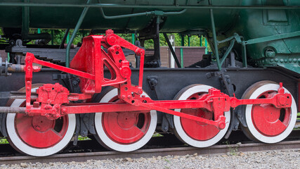 Red and white iron wheel set with coupling rod (side rod) of the old retro steam locomotive close up  