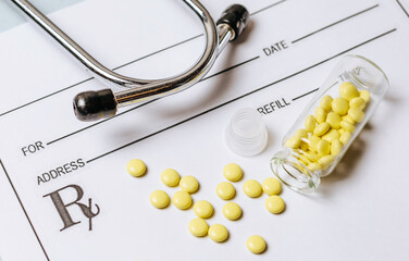 Medical concept. Yellow pills with stethoscope, pills, notepad, medical prescription on the doctor's desktop. Treating a patient in a hospital with medication.