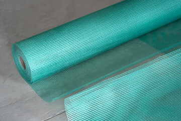 Close-up of green blue reinforcing mesh rolled up. A building resource for reinforcing walls in the...