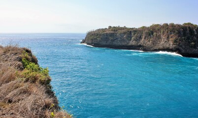 Fototapeta na wymiar Scenic view of cliffs and blue ocean water in Nusa Penida, Indonesia