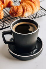 Croissants on cooling rack and cup of coffee.