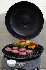 hamburger meat and peppers on black barbecue outside