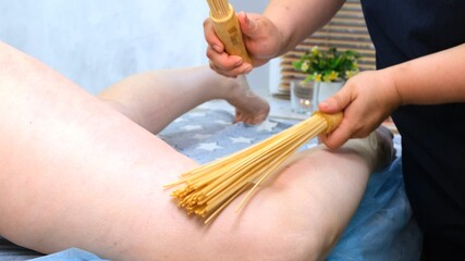 Anti-cellulite massage with bamboo sticks for a fat woman. Aggressive fight against fat. Spa treatment.