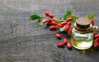 Barberry essential oil in a glass bottle on old wooden table for aromatherapy,skin care or spa.Berberis vulgaris herb extract.Selective focus.