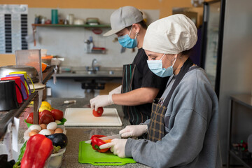 two young businessmen cooks, cooking and handling food with chinstrap and gloves for precaution and hygiene