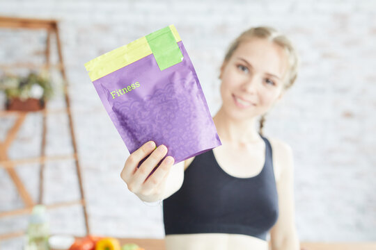The girl is holding a package of sports nutrition. Protein for training.