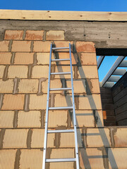 Aluminium ladders close to brick wall