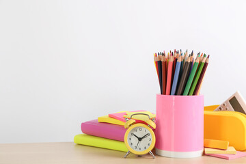 Fototapeta premium Different school stationery and alarm clock on table against white background, space for text. Back to school