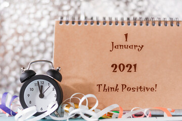 Motivational quote think positive. Retro alarm clock in a new year's environment next to an open Notepad.