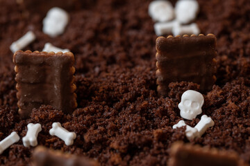 Kuchen als Friedhof mit Gräbern und Skeletten aus Schokokrümel, Creme und Banane auf Tisch aus...