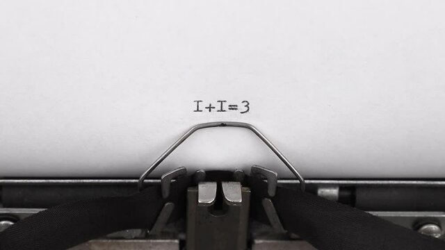 typing numerals 1+1=3 on a vintage typewriter close-up. concept of teamwork