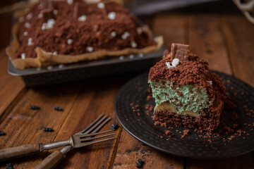 Kuchen als Friedhof mit Gräbern und Skeletten aus Schokokrümel, Creme und Banane auf Tisch aus Holz und dahinter Spinnweben