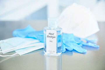 Hand sanitizer face masks and latex medical gloves on stainless steel surface