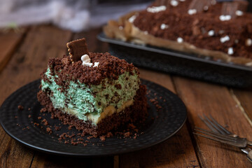 Kuchen als Friedhof mit Gräbern und Skeletten aus Schokokrümel, Creme und Banane auf Tisch aus Holz und dahinter Spinnweben
