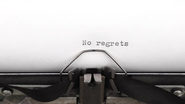typing a quote no regrets on a vintage typewriter close-up