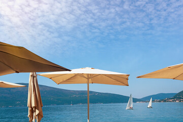 Vacation concept. Sun umbrellas against blue sky. Montenegro, Adriatic Sea. View of Kotor Bay near Tivat city