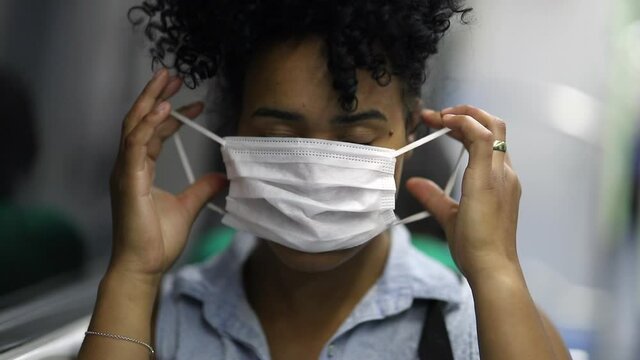 Young black African American woman putting surgical mask while riding metro subway
