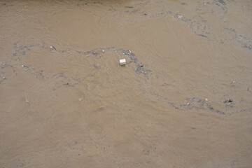 River canal in a big city. Sewage after rain carries garbage along the river.