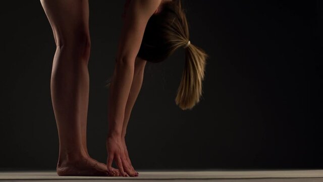Girl practicing yoga. Stretching arms and legs. Hands touching feet and gorund.