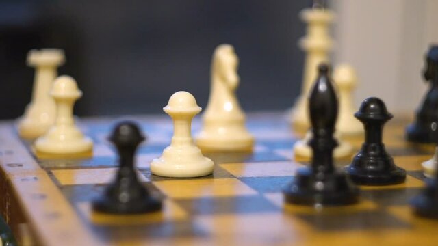 A man's hand moves a chess piece. Board game. Black and white pieces. White pawn. Strategic solution. Business thinking. Close-up.