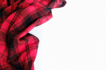 Bright red plaid wrinkled shirt on a white background. Environment for working or studying from home. Empty surface surrounded by soft warm material. Cozy home office desk setting for isolation.