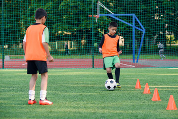 Two teen boys passes soccer ball each other on the football stadium. Teamwork and joint training concept.