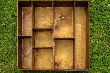 Wooden box with empty compartments, on green grass