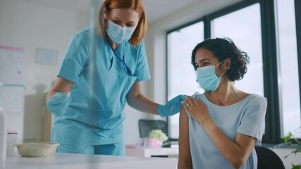 Medical Nurse in Safety Gloves and Protective Mask is Making a Vaccine Injection to a Female Patient in a Health Clinic