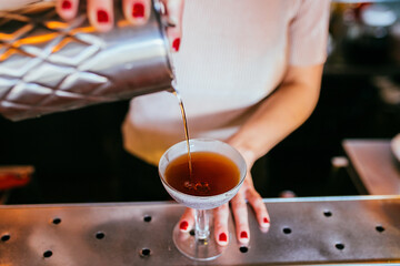 mujer bartender sirviendo un cocktail en una copa