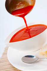 Close-up of tomato soup being poured into a bowl