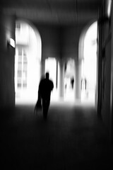 Motion blur image in black and white of man walking in urban environment.