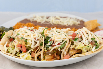 Three shrimp tacos loaded with extras with  rice and beans served on a hot plate for some delicious Mexican food.