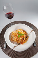 Close-up of pepper and basil garnished pasta with red wine