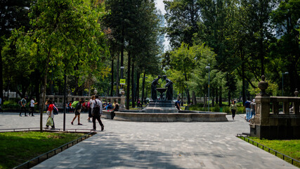 Obraz premium Fountain of Two Women Pouring Down Water Into a Bird Waterer in the Middle of a Park