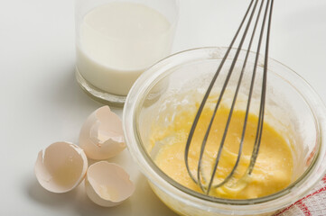 Metal whisk stirring egg mixture in a bowl