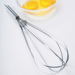 Close-up of a wire whisk and egg yolk in a bowl