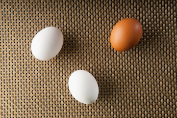 Close-up of a brown egg with two white eggs