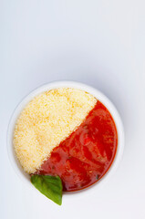 High angle view of a bowl of tomato sauce and grated cheese