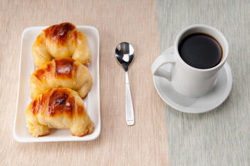 High angle view of croissants served with a cup of a cup of black coffee