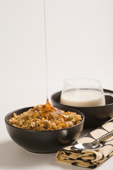 Honey pouring into breakfast cereal with milk