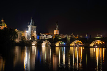 Fototapeta na wymiar panorama of charles bridge .monument from 14th century and shining street lamp on it. and on the surface of the Vltava River there are reflections from the lights. at night in the center of Prague