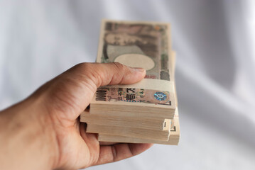 Hand holding 10000 yen bills isolated on white background.
