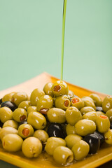 Olive oil being poured on black and green olives