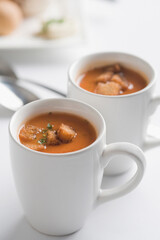 Close-up of two cups of tomato soup with bread cubes