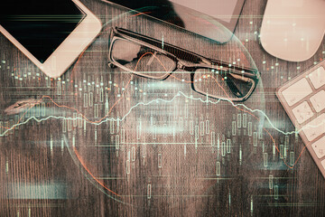 Multi exposure of forex graph hologram over desktop with phone. Top view. Mobile trade platform concept.