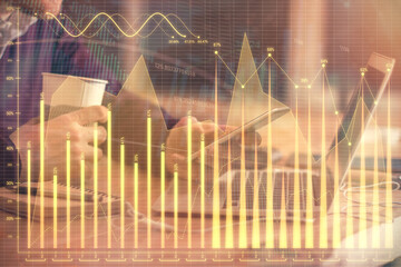 Double exposure of man's hands holding and using a phone and financial graph drawing. Analysis concept.