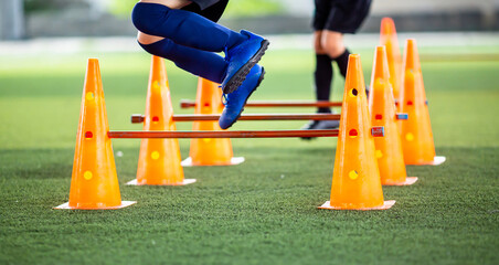 Selective focus to kid soccer player Jogging and jump cross cone and hurdles marker. Kid soccer...