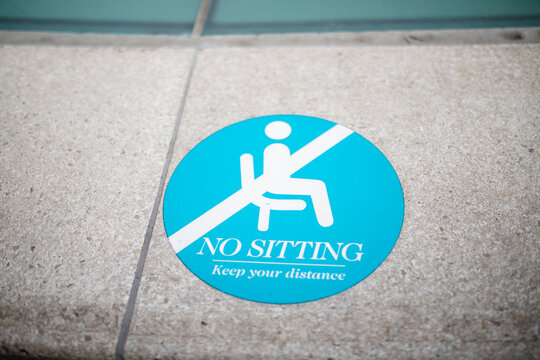 A "No Sitting" Round Sign on the Sidewalk